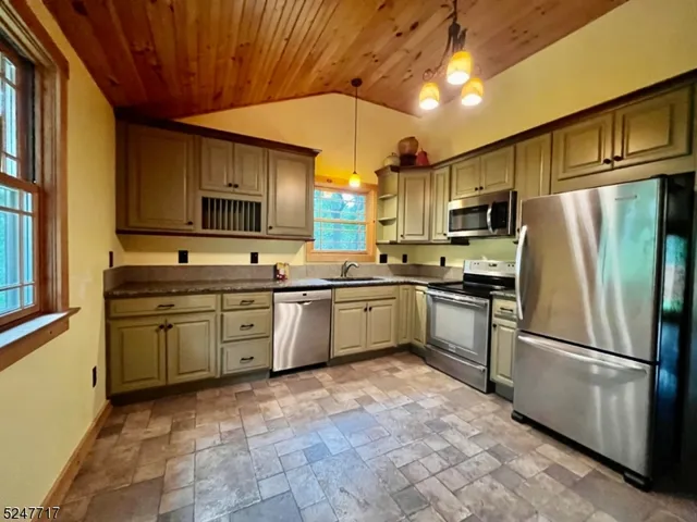 a kitchen with kitchen island a counter top space cabinets stainless steel appliances and a window