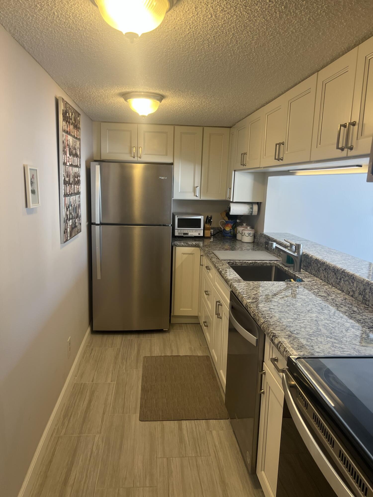 1605 Highway 1, Unit 201M2 Jupiter, FL 33477 - Photo 12 of 47 a kitchen with a sink a refrigerator and cabinets