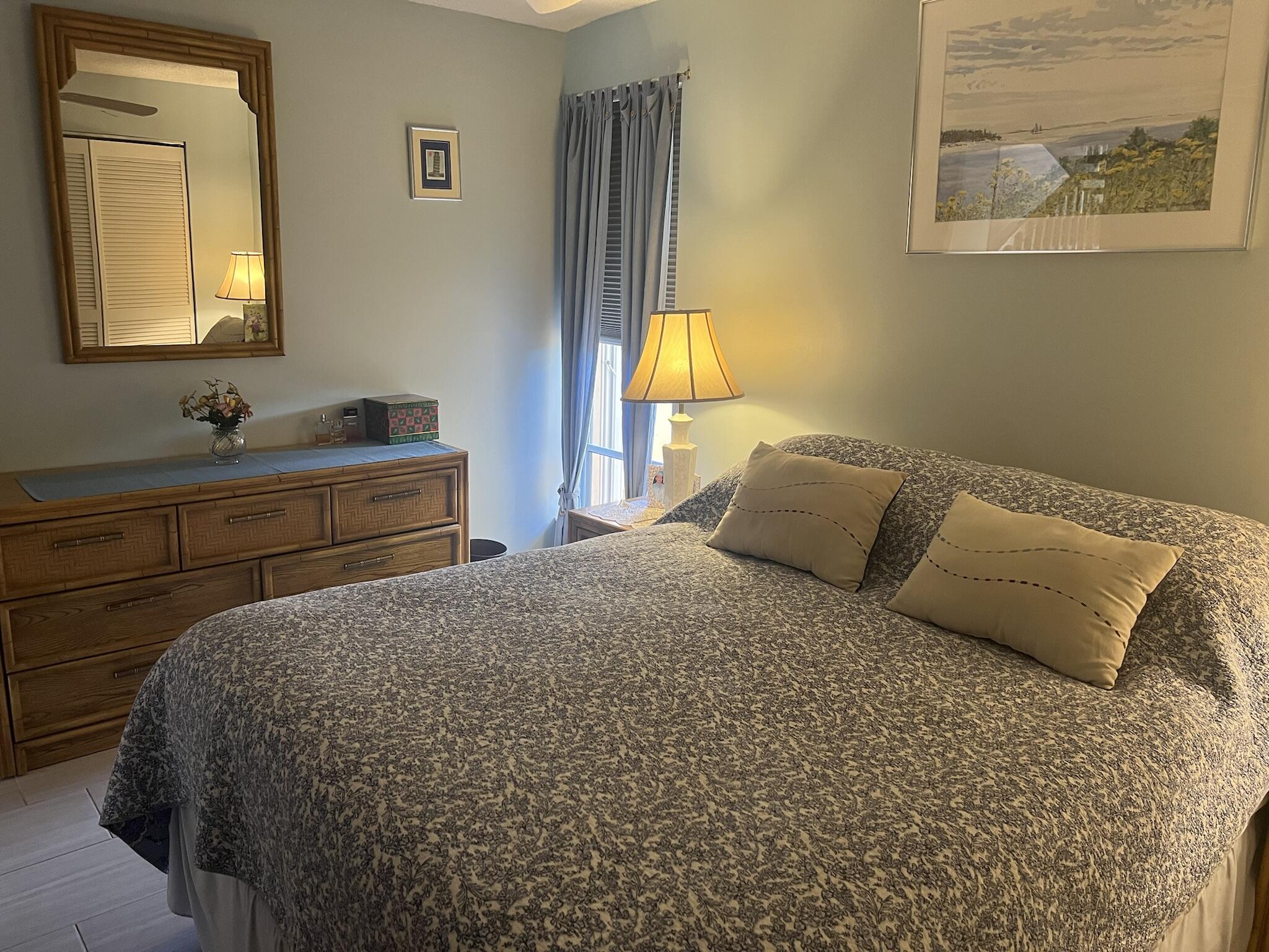 1605 Highway 1, Unit 201M2 Jupiter, FL 33477 - Photo 17 of 47 a bedroom with a bed and a lamp on dresser