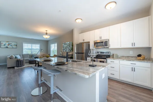a kitchen with stainless steel appliances a stove a sink a refrigerator a center island and furniture