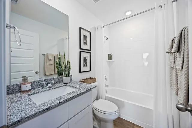 a bathroom with a granite countertop sink a toilet and shower