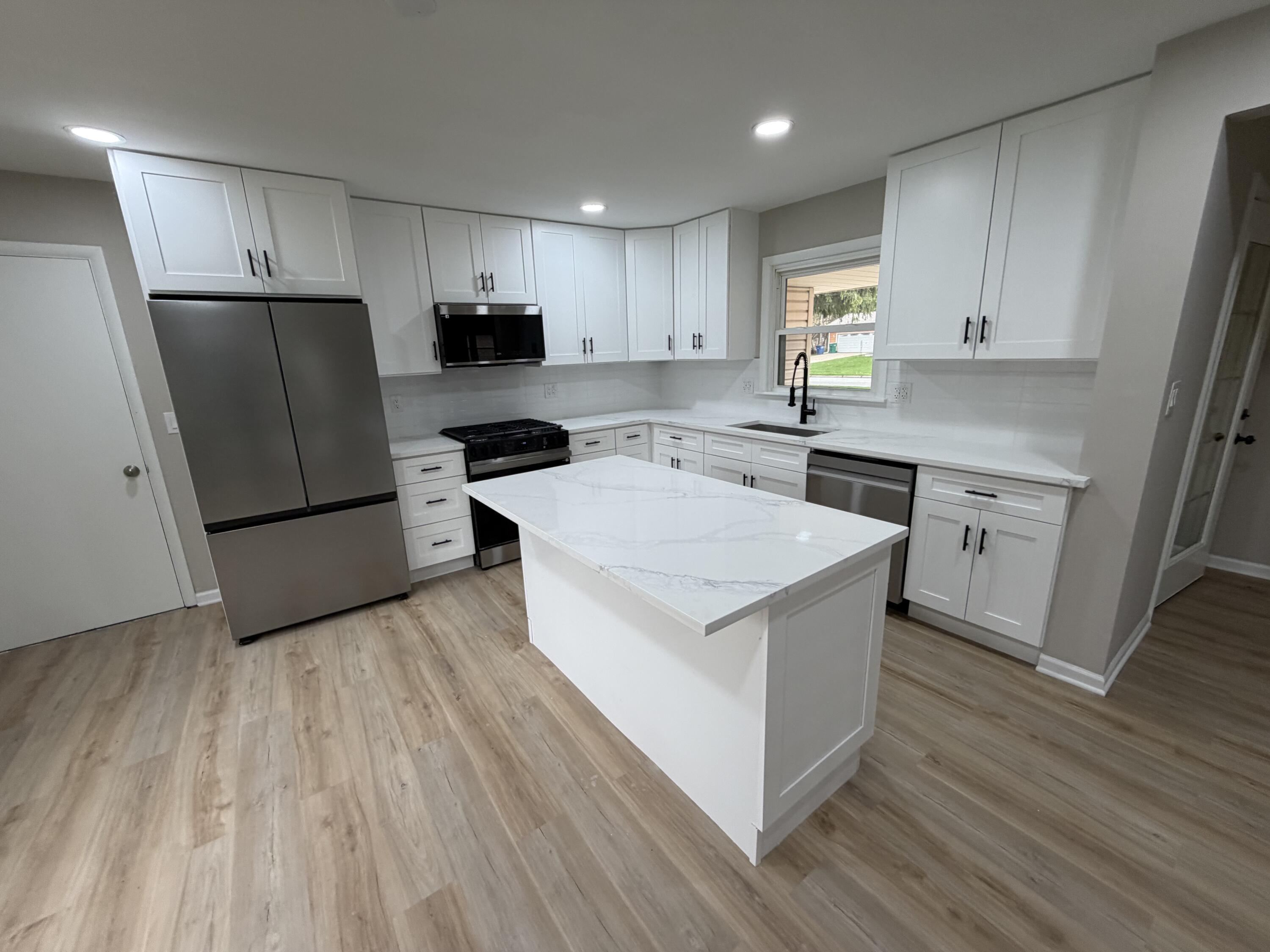 603 West 13th Street La Porte, IN 46350 - Photo 5 of 18 a kitchen with a sink a refrigerator a microwave and cabinets