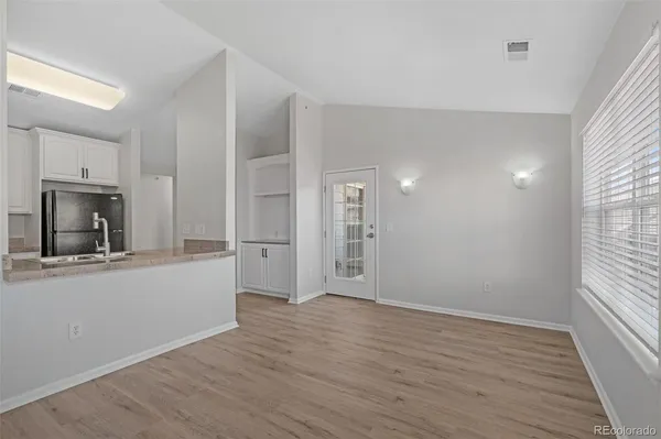a view of a kitchen and an empty room with wooden floor and a window