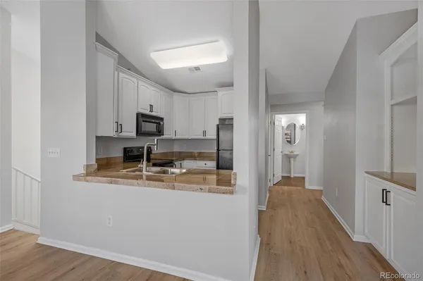a view of a kitchen with kitchen island a sink wooden floor and stainless steel appliances