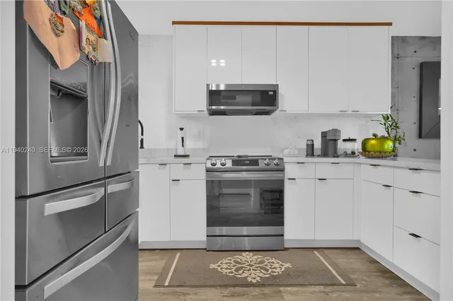 a kitchen with stainless steel appliances granite countertop a refrigerator a stove and a sink