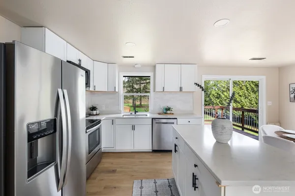 a kitchen with stainless steel appliances granite countertop a refrigerator a stove a sink a microwave and white cabinets