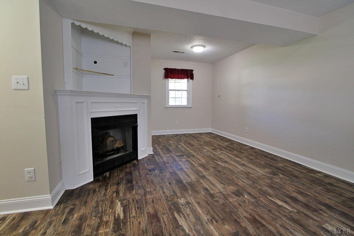 2899 Thomas Jefferson Road Forest, VA 24551 - Photo 12 of 22 an empty room with wooden floor and a fireplace