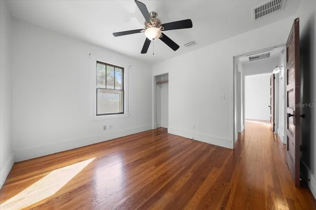 a view of empty room with wooden floor and fan