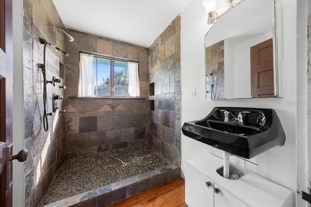 a bathroom with a granite countertop sink a toilet a mirror and shower