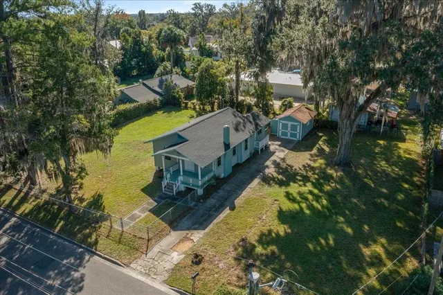 an aerial view of a house with swimming pool and large trees