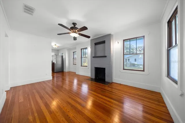 a view of empty room with wooden floor and fan