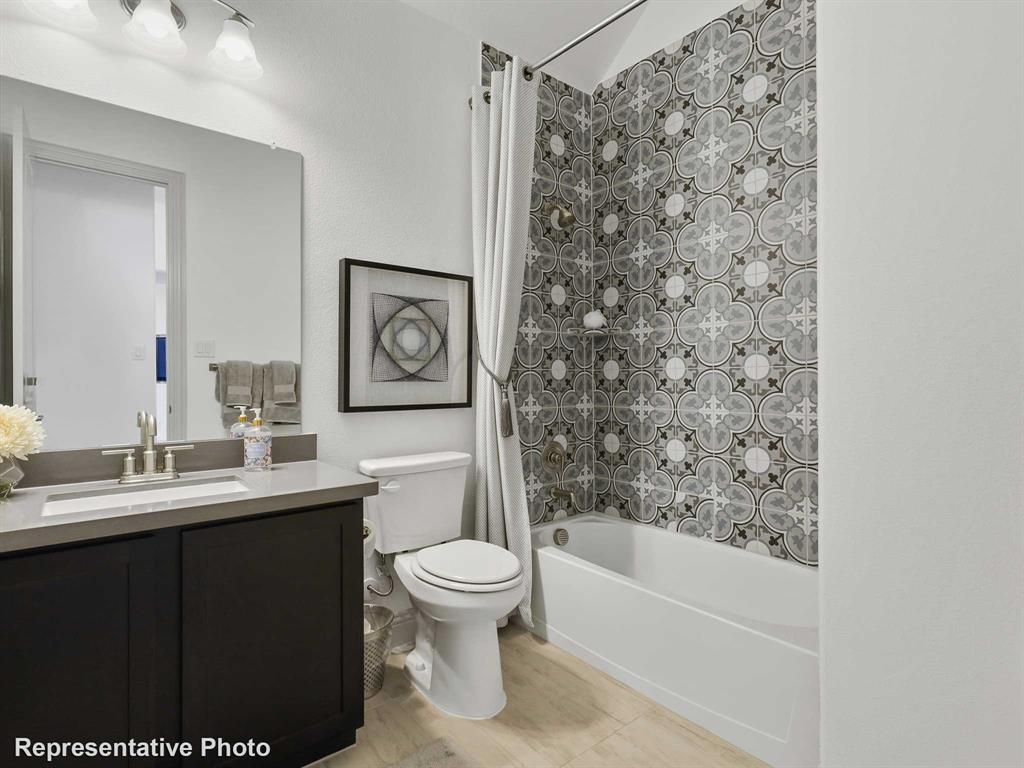 2204 Ridgecrest Lane Anna, TX 75409 - Photo 14 of 17 Bathroom featuring a patterned shower surround, white bathtub, dark wood-finish vanity with a light countertop, and a vanity mirror with overhead lighting