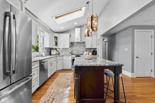 a kitchen with stainless steel appliances granite countertop a sink a stove a refrigerator cabinets and chairs