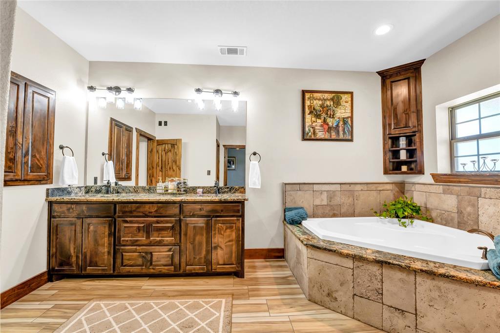 854 County Road 3330 Bridgeport, TX 76426 - Photo 13 of 40 The spa like bathroom has real wood double vanities with granite countertops, built in medicine cabinet and a corner accent cabinet for towels.