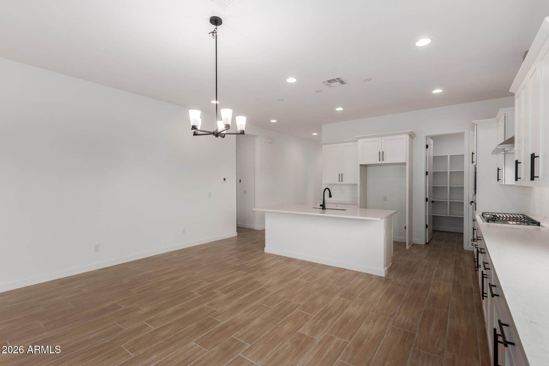 15890 West Miami Street Goodyear, AZ 85338 - Photo 9 of 51 a large white kitchen with a refrigerator a sink dishwasher a oven and a dining table with wooden floor