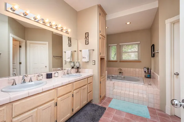 a spacious bathroom with a double vanity sink a mirror and a bathtub