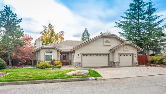 a front view of a house with a garden and trees