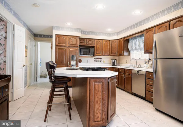 a kitchen with stainless steel appliances granite countertop a refrigerator a sink a stove a microwave and a dining table with wooden floor