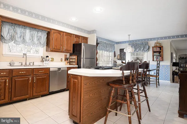 a kitchen with stainless steel appliances kitchen island granite countertop a table chairs sink and cabinets
