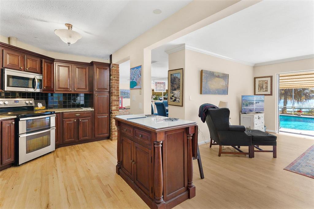 475 Guerrant Street Umatilla, FL 32784 - Photo 15 of 63 a kitchen with a stove top oven a sink dishwasher a dining table and chairs with wooden floor