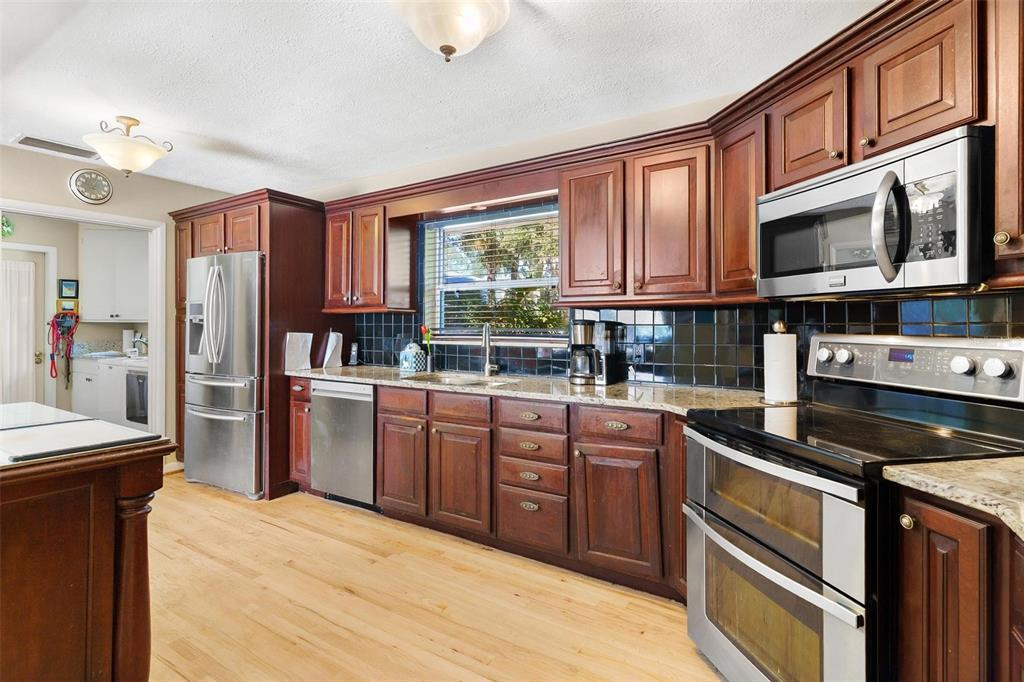 475 Guerrant Street Umatilla, FL 32784 - Photo 40 of 63 a kitchen with stainless steel appliances granite countertop a stove sink and cabinets