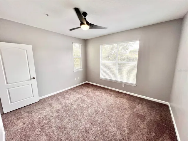 a view of empty room with window and ceiling fan