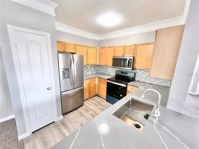 a kitchen with granite countertop a refrigerator and a stove top oven