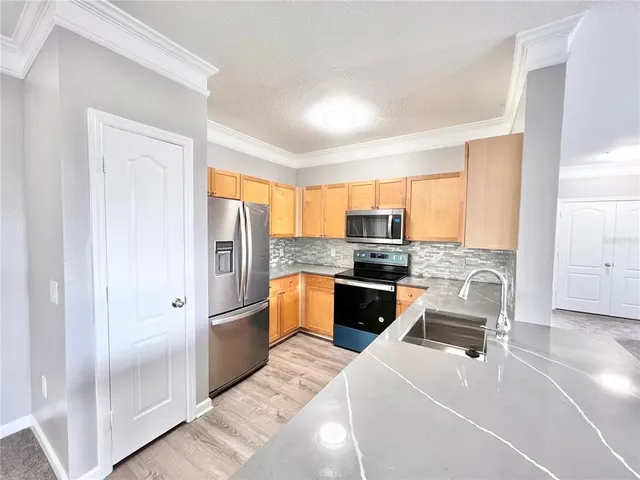 a kitchen with a refrigerator a stove top oven a sink and dishwasher with wooden floor