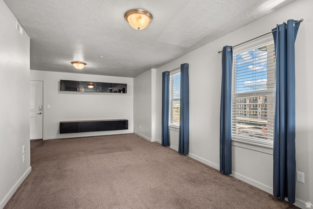 1700 South Sandhill Road West, Unit E 301 Orem, UT 84058 - Photo 5 of 20 Carpeted room featuring two windows with horizontal blinds, a white door, and two flush-mount ceiling lights