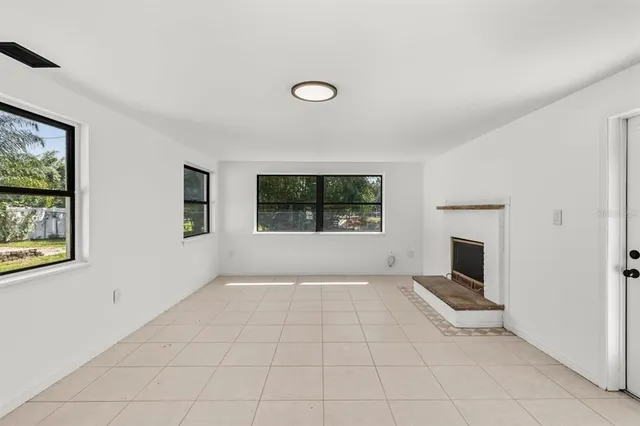 an empty room with windows and fireplace