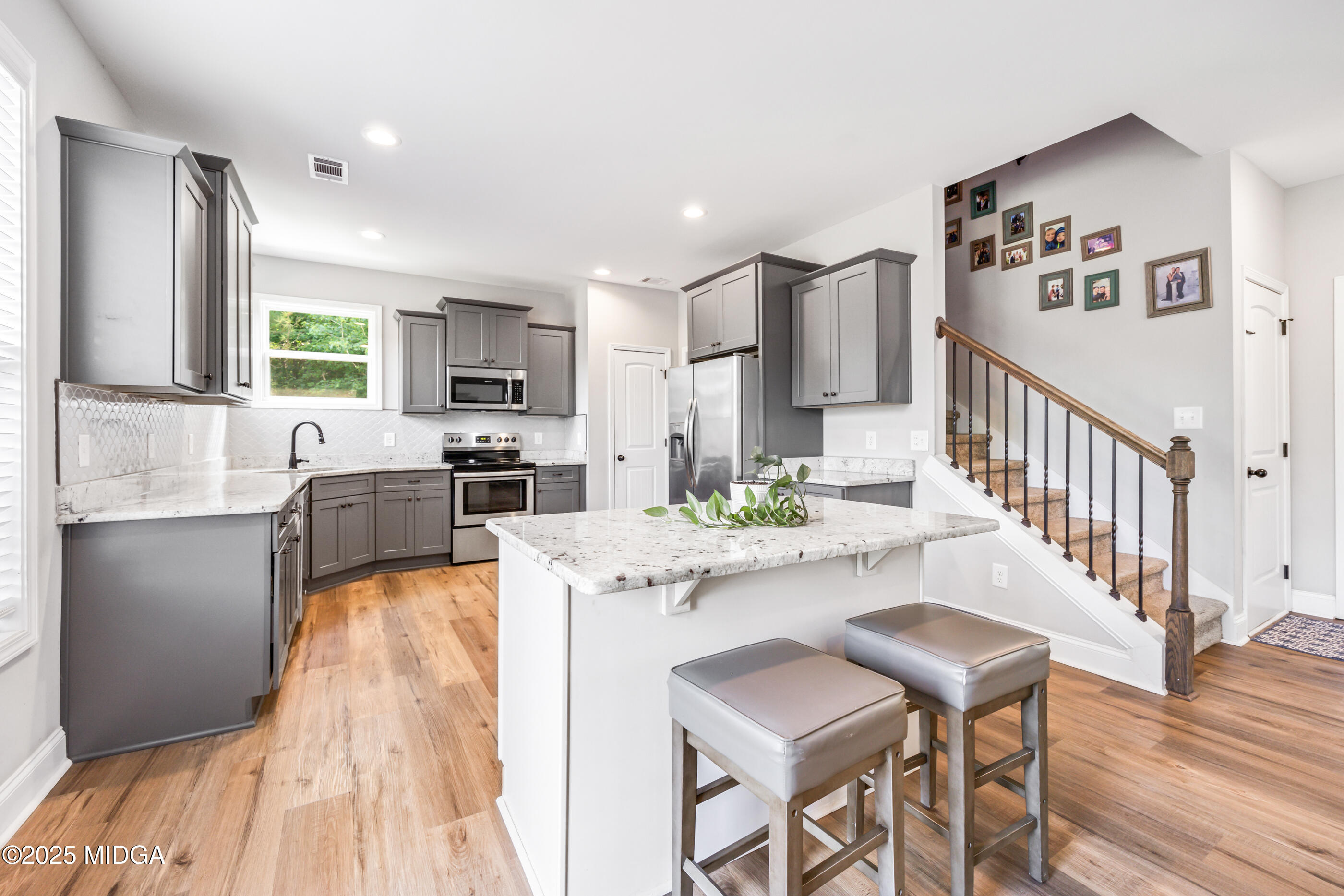 36 River Rapids Drive Forsyth, GA 31029 - Photo 11 of 57 a kitchen with stainless steel appliances granite countertop a refrigerator a stove top oven a sink dishwasher and white cabinets with wooden floor