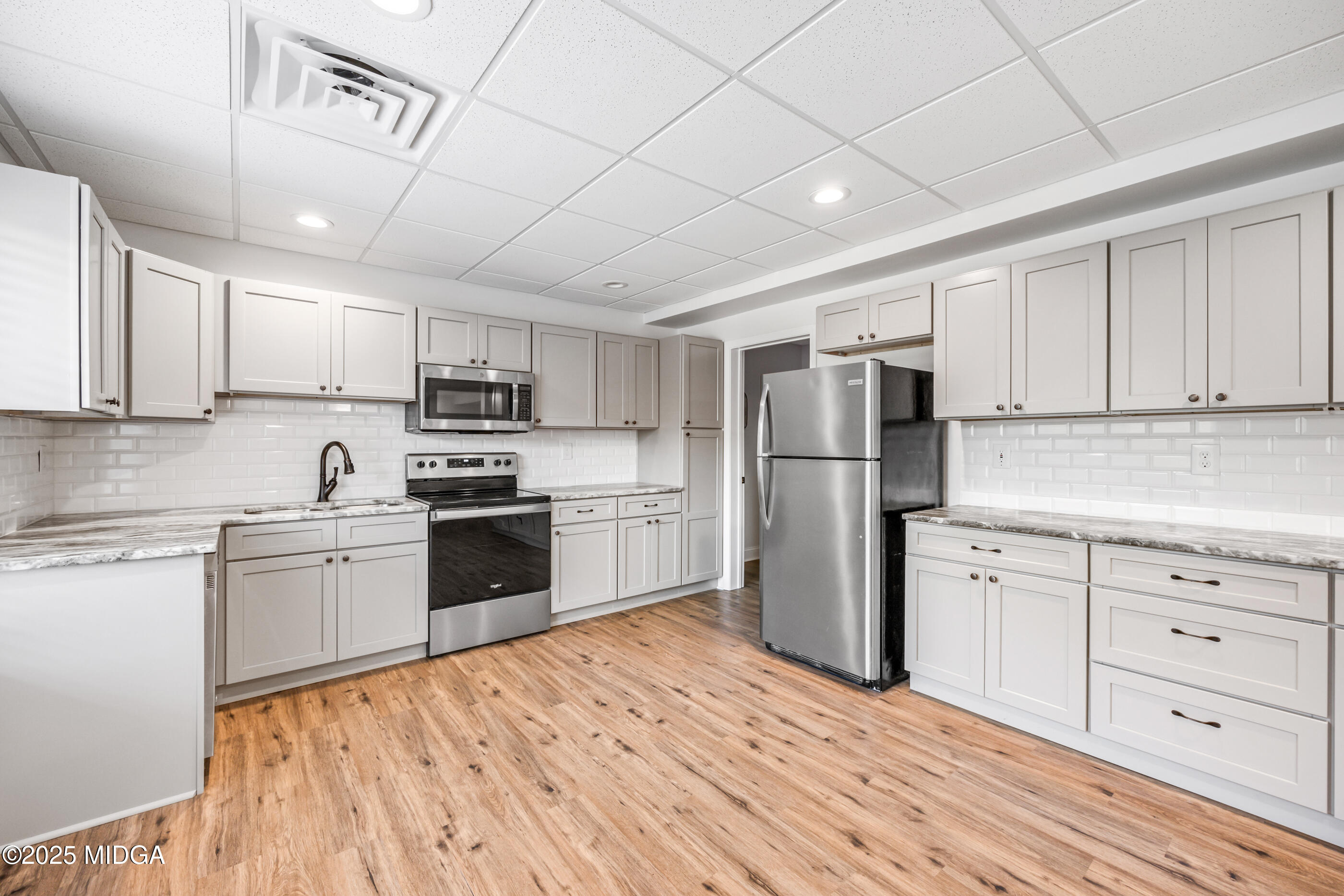 36 River Rapids Drive Forsyth, GA 31029 - Photo 28 of 57 a kitchen with a refrigerator stove and white cabinets with wooden floor