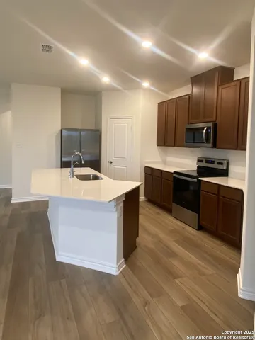 a large kitchen with stainless steel appliances a sink a stove and a wooden floors