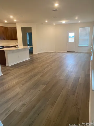 a view of an empty room with kitchen and a sink