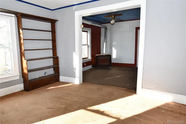 a view of an empty room with window and hardwood floor