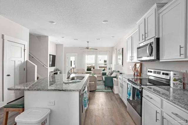 a kitchen with stainless steel appliances granite countertop a sink stove microwave and refrigerator