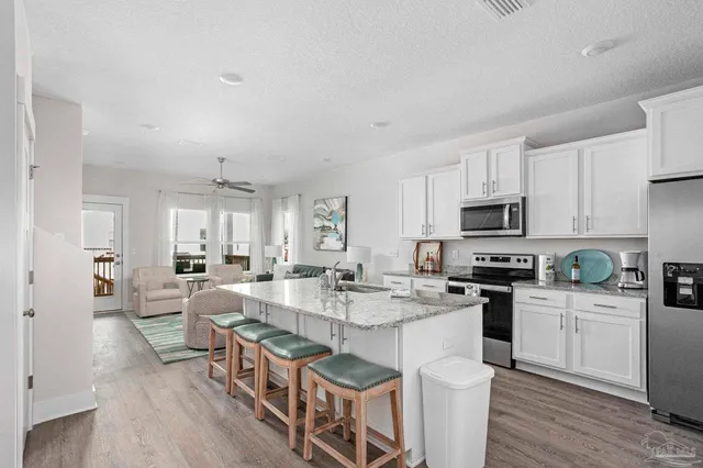 a very nice looking open kitchen with granite countertop a stove top oven a sink a dining table and chairs