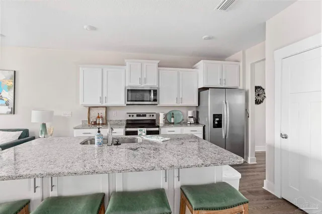 a kitchen with stainless steel appliances granite countertop a sink a microwave a refrigerator and white cabinets
