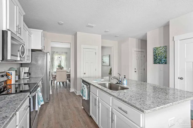 a kitchen with stainless steel appliances granite countertop a sink refrigerator and cabinets