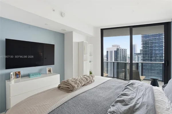 a bedroom with a bed and a flat tv screen next to a large window