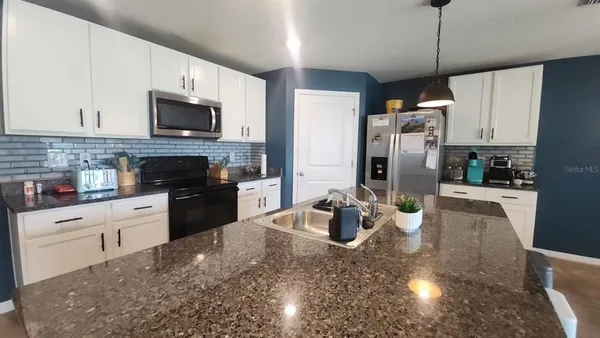 a kitchen with stainless steel appliances granite countertop a refrigerator stove microwave and sink