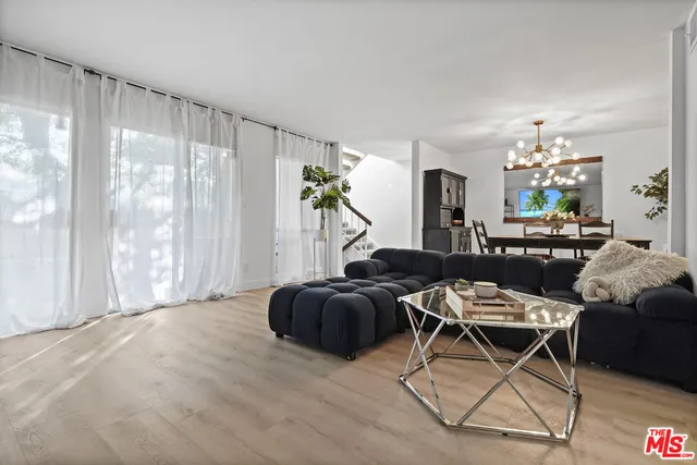 a dining room with wooden floor a chandelier a wooden table and chairs