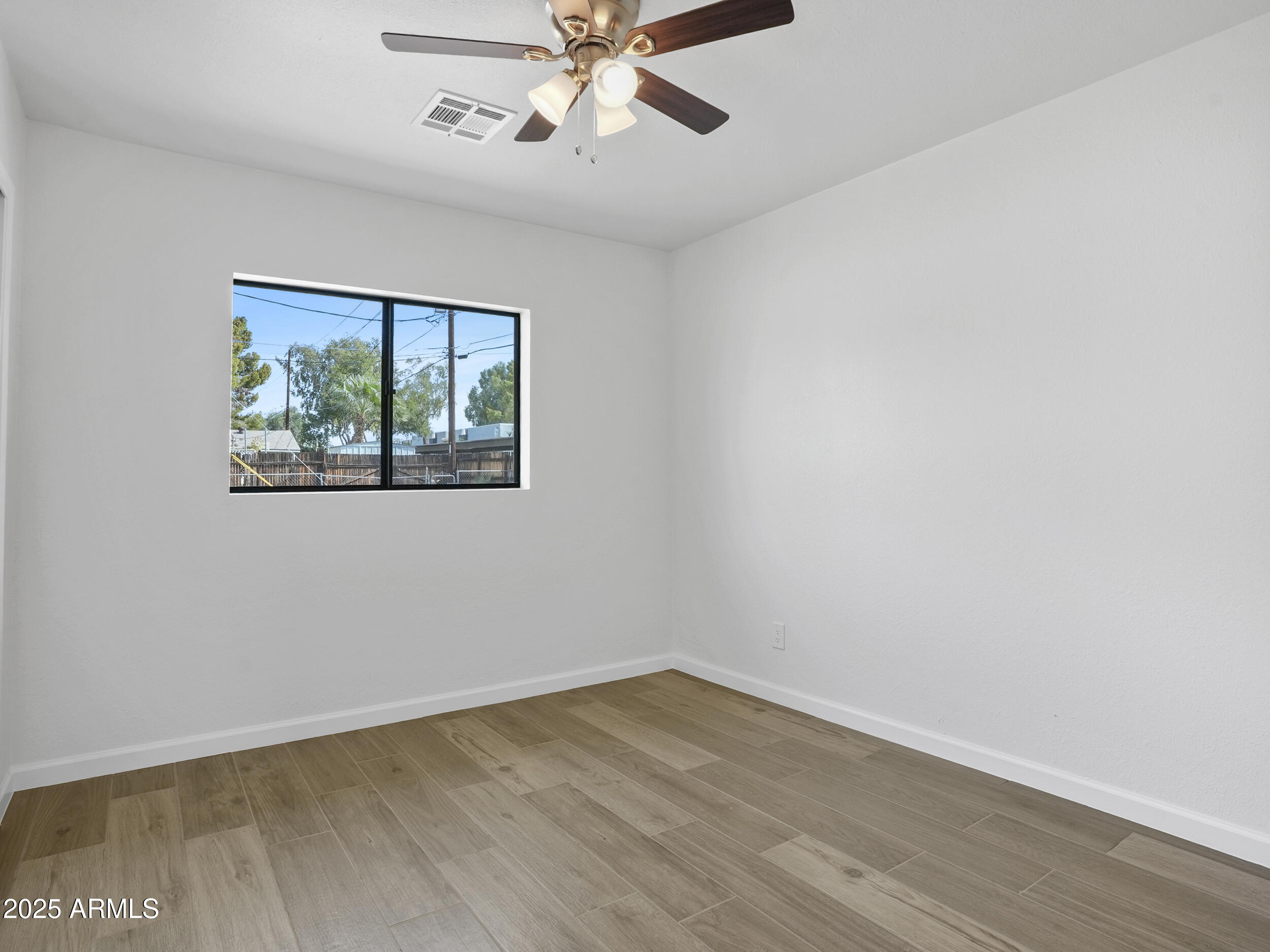 1046 East Elm Street Phoenix, AZ 85014 - Photo 24 of 31 an empty room with wooden floor chandelier fan and windows