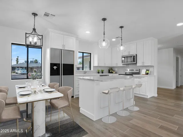 a open kitchen with stainless steel appliances granite countertop a stove a refrigerator a kitchen island a dining table and chairs