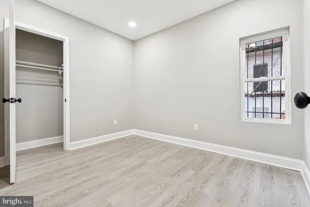 a view of an empty room with wooden floor and windows