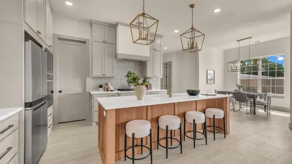 a kitchen with granite countertop a table chairs stainless steel appliances and cabinets