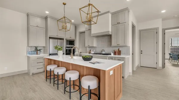 a kitchen with stainless steel appliances a sink a stove a refrigerator cabinets and chairs