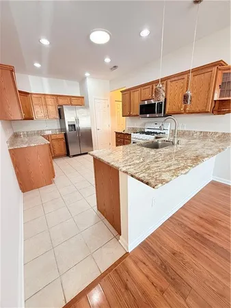 a large kitchen with stainless steel appliances kitchen island granite countertop a large counter top and view of living room