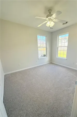 an empty room with windows and chandelier fan