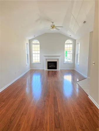 an empty room with wooden floor fireplace and windows